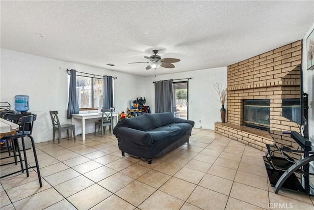 living area featuring light tile patterned floors, visible vents, ceiling fan, and a fireplace