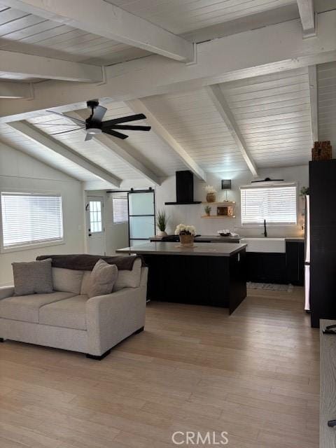 living area featuring a wealth of natural light, lofted ceiling with beams, and light wood-style floors