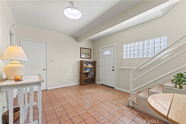 entrance foyer with light tile patterned floors, baseboards, and stairs