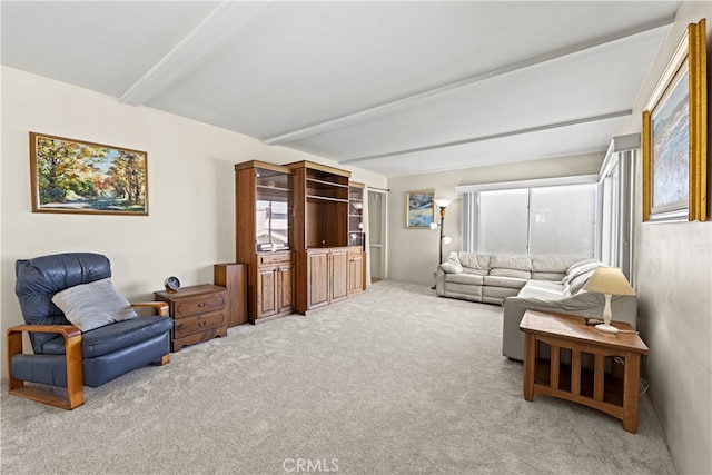 living area featuring beamed ceiling and light colored carpet