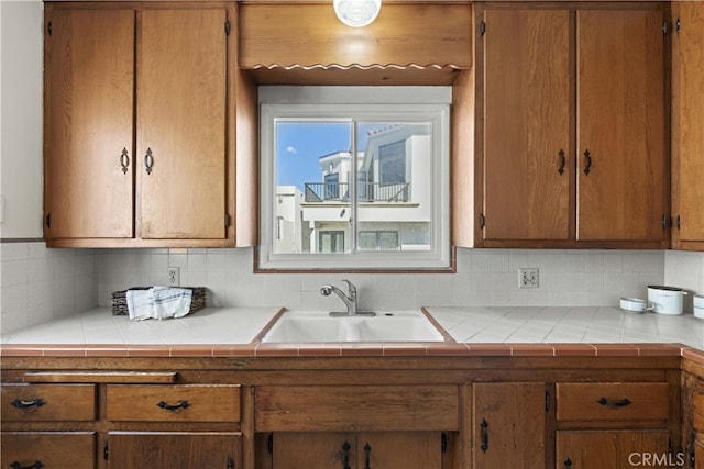 kitchen featuring backsplash, brown cabinets, and a sink