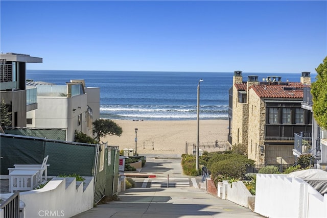 view of water feature featuring a view of the beach and fence