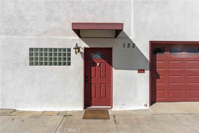 doorway to property with stucco siding and a garage