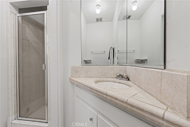 bathroom featuring visible vents, a stall shower, and vanity