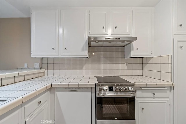 kitchen with electric range, decorative backsplash, tile counters, under cabinet range hood, and white cabinetry