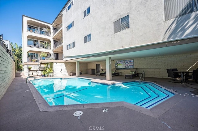 community pool with a patio area and stairs