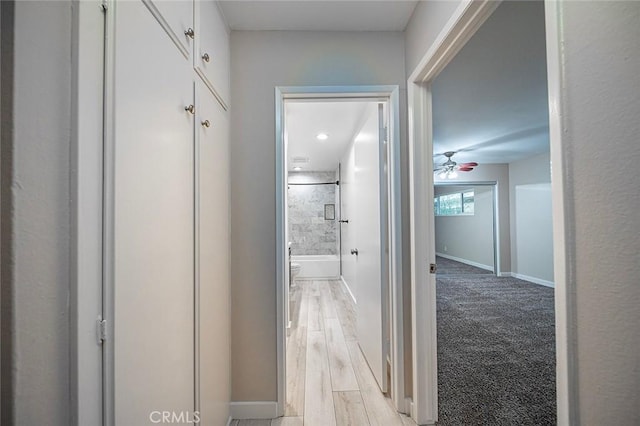 hallway featuring light wood-style flooring and baseboards