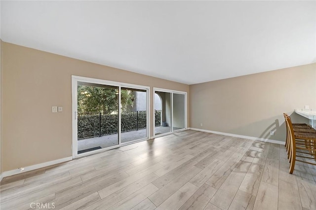 unfurnished living room featuring baseboards and light wood-style floors