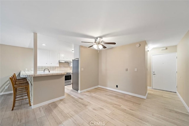 kitchen with tasteful backsplash, tile countertops, stainless steel fridge, stove, and white cabinets