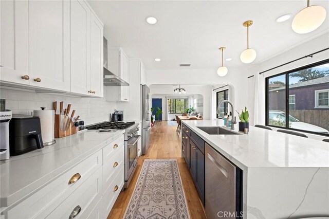 3345 Oakhurst Ave, Los Angeles, CA 90034 - kitchen with stainless steel appliances, a sink, wall chimney range hood, a center island with sink, and white cabinetry