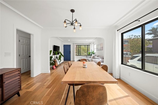 3345 Oakhurst Ave, Los Angeles, CA 90034 - dining area featuring a chandelier, light wood-style floors, crown molding, arched walkways, and baseboards