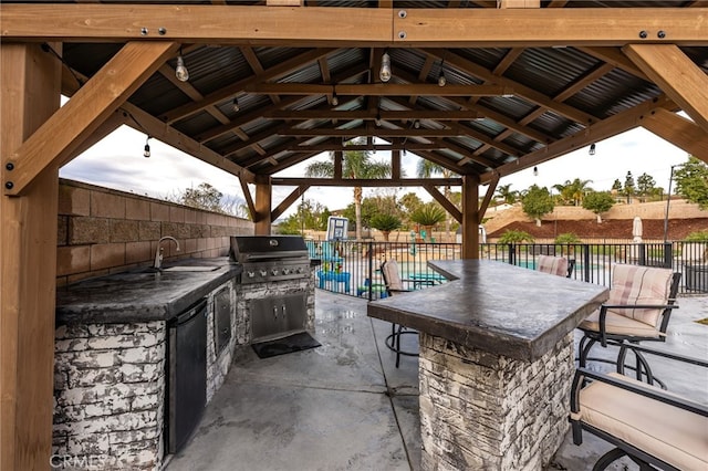 view of patio with a sink, a fenced backyard, a grill, and exterior kitchen