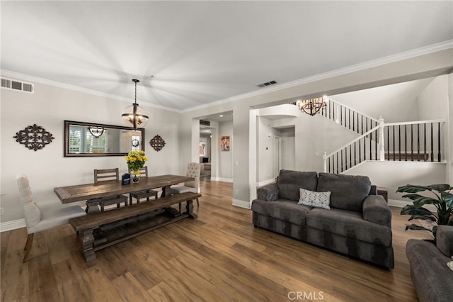 living area featuring stairs, an inviting chandelier, wood finished floors, and visible vents