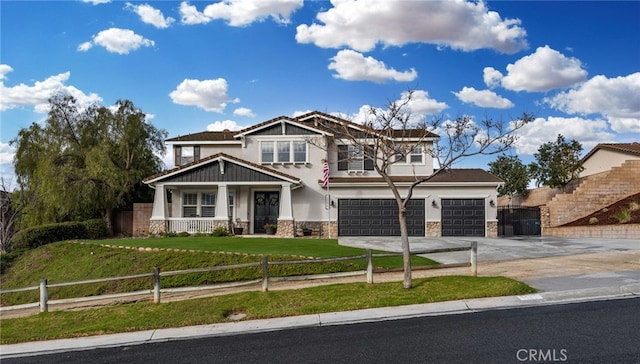 craftsman-style house featuring stone siding, driveway, a fenced front yard, and stucco siding