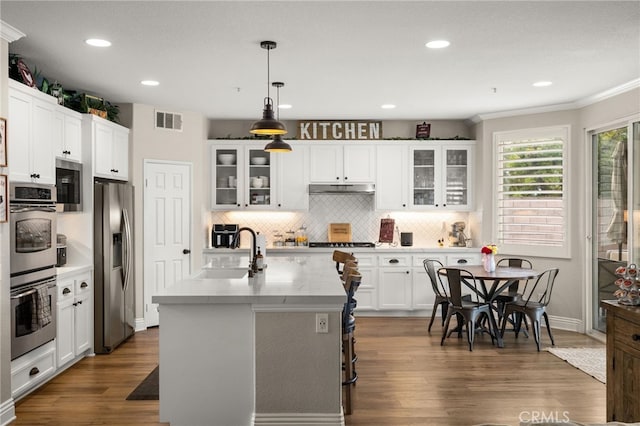 kitchen with visible vents, a sink, under cabinet range hood, stainless steel appliances, and decorative backsplash