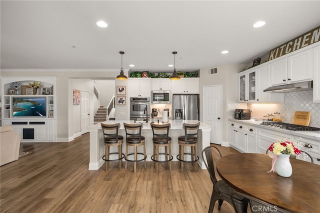 kitchen featuring visible vents, stainless steel appliances, white cabinets, glass insert cabinets, and under cabinet range hood