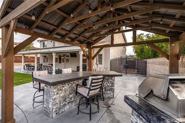 view of patio featuring a bar, area for grilling, exterior kitchen, and fence