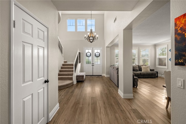 entryway featuring visible vents, wood finished floors, an inviting chandelier, baseboards, and stairs