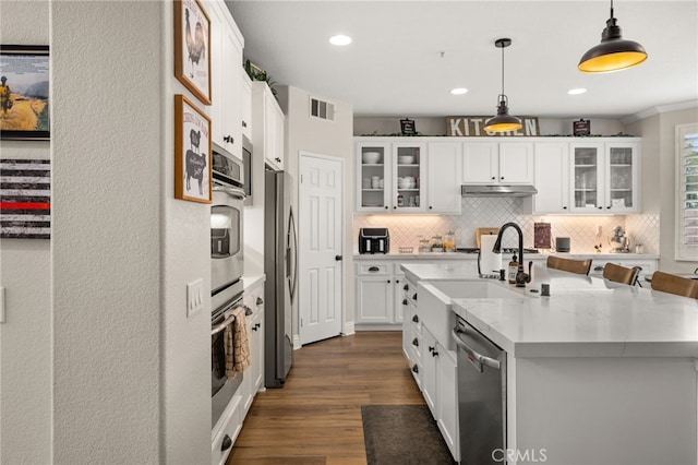 kitchen featuring visible vents, white cabinets, under cabinet range hood, appliances with stainless steel finishes, and backsplash