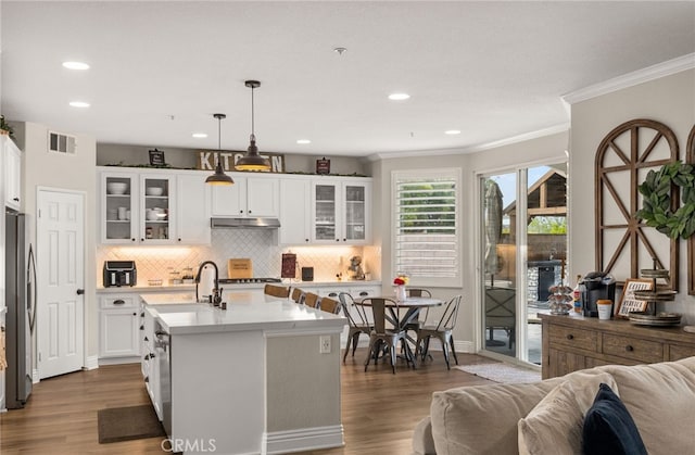 kitchen featuring visible vents, dark wood-style flooring, freestanding refrigerator, light countertops, and under cabinet range hood