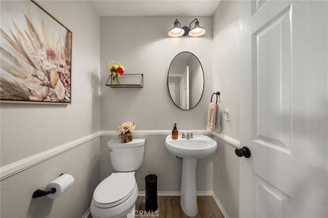 bathroom with toilet, wood finished floors, and baseboards