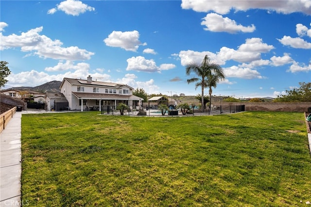 rear view of house with a yard and a fenced backyard