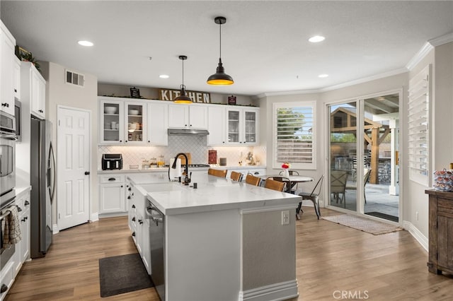 kitchen featuring visible vents, backsplash, under cabinet range hood, wood finished floors, and stainless steel appliances