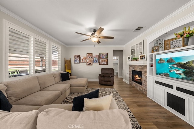 living room with visible vents, crown molding, a fireplace, wood finished floors, and a ceiling fan