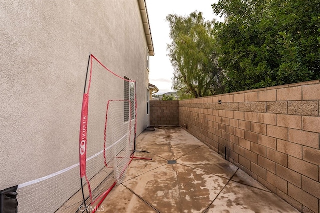 view of side of property with a patio area, a fenced backyard, and stucco siding