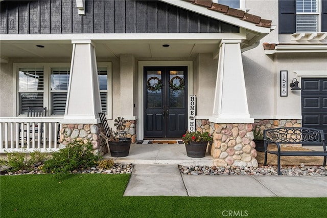 doorway to property with french doors, covered porch, and stone siding