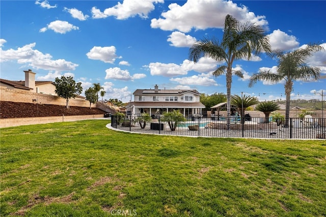 back of property featuring fence, a fenced in pool, a yard, a patio area, and roof mounted solar panels