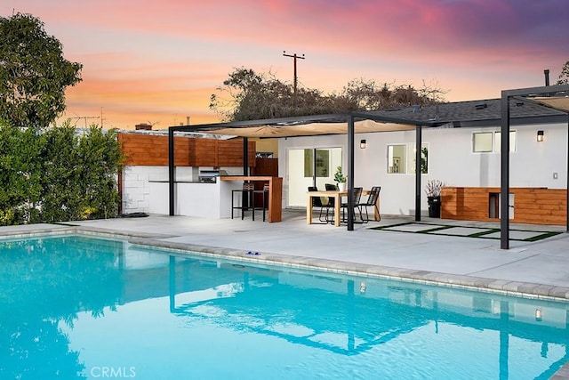 pool at dusk with a patio, fence, a fenced in pool, area for grilling, and outdoor dry bar