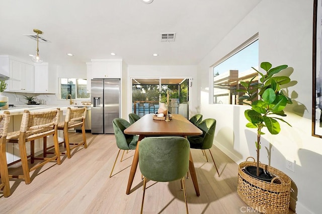 dining room featuring visible vents, a healthy amount of sunlight, and light wood-type flooring