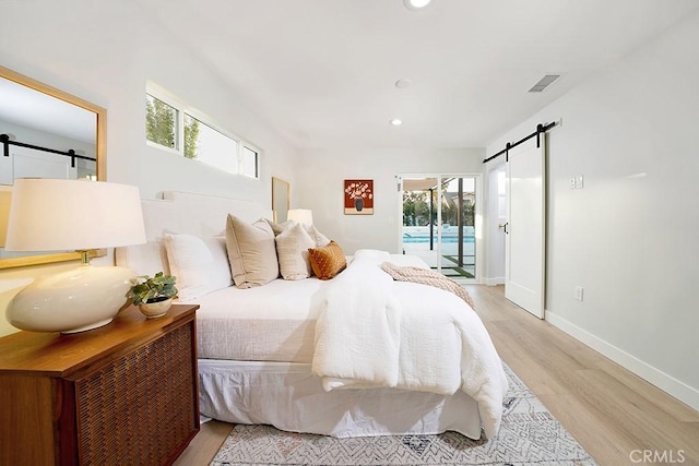 bedroom featuring access to exterior, visible vents, baseboards, a barn door, and light wood-style floors