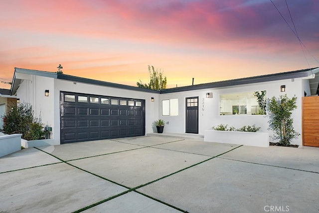 view of front of house featuring an attached garage, fence, driveway, and stucco siding