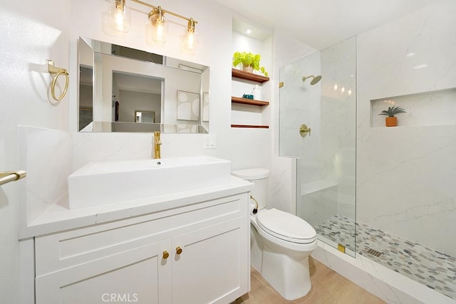 full bathroom featuring a marble finish shower, toilet, vanity, and wood finished floors