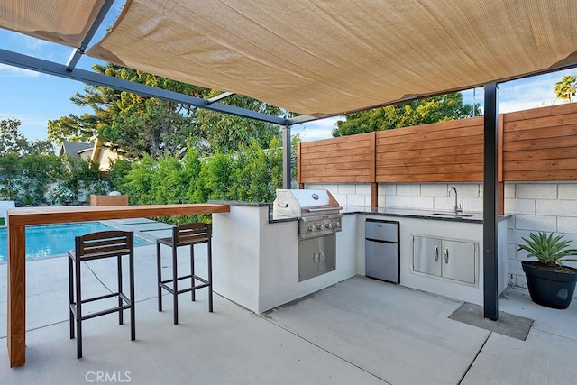 view of patio / terrace with grilling area, fence, outdoor wet bar, area for grilling, and a sink