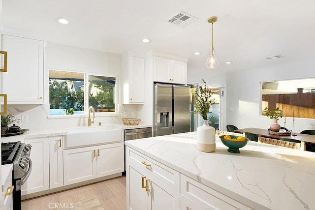 kitchen with tasteful backsplash, visible vents, appliances with stainless steel finishes, white cabinetry, and a sink