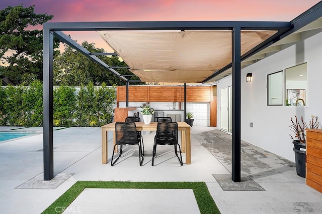 patio terrace at dusk with outdoor dining space and fence