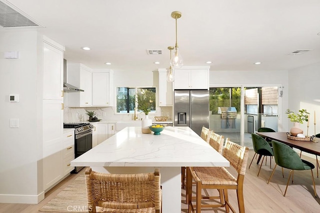 kitchen with visible vents, appliances with stainless steel finishes, and wall chimney exhaust hood