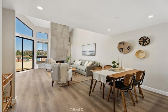 dining area featuring recessed lighting, light wood-style flooring, a tile fireplace, and baseboards