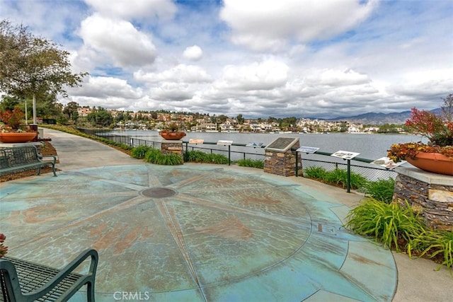 view of patio featuring a water view and fence