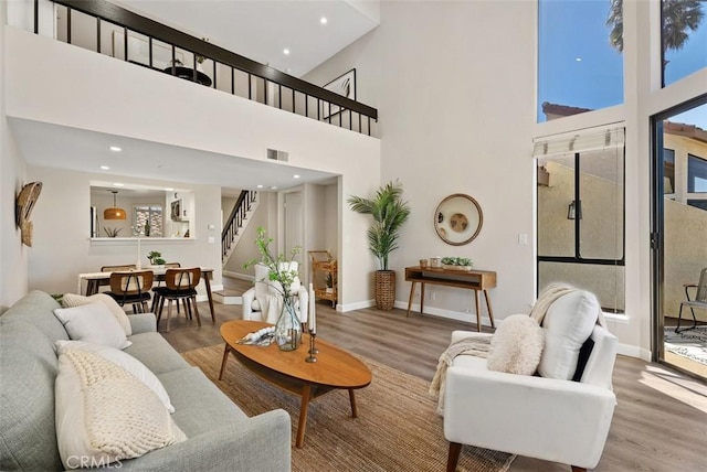 living room with stairway, baseboards, visible vents, and wood finished floors