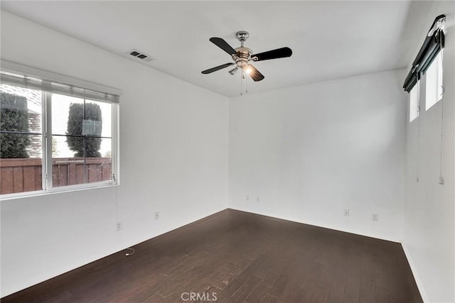 empty room featuring dark wood finished floors, visible vents, and ceiling fan