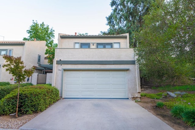 view of front facade featuring stucco siding, driveway, and a garage