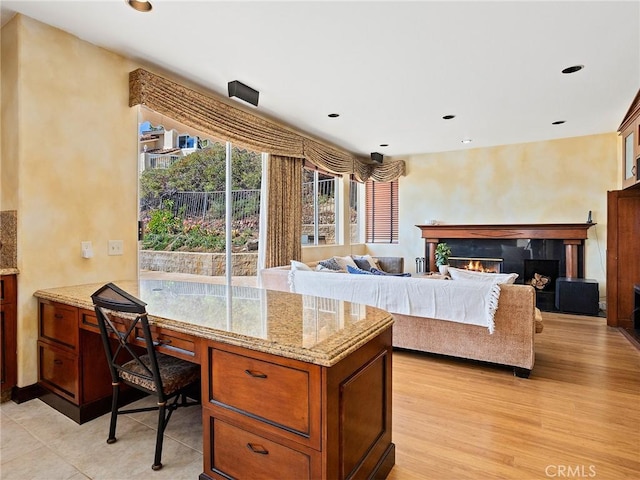 interior space with recessed lighting, light wood-style flooring, and a warm lit fireplace