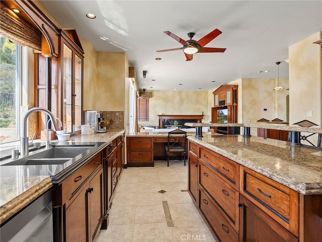 kitchen with light stone counters, a ceiling fan, recessed lighting, a sink, and a kitchen breakfast bar