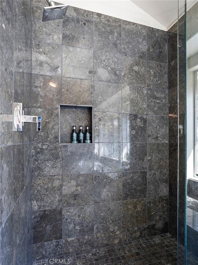 full bath featuring lofted ceiling and a tile shower