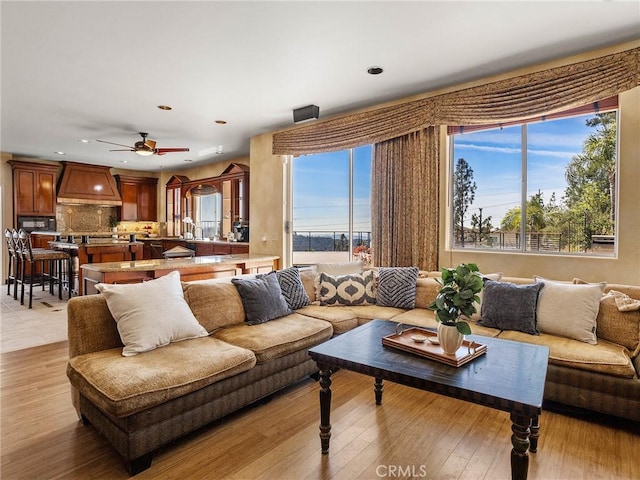 living area with a ceiling fan, recessed lighting, and light wood finished floors