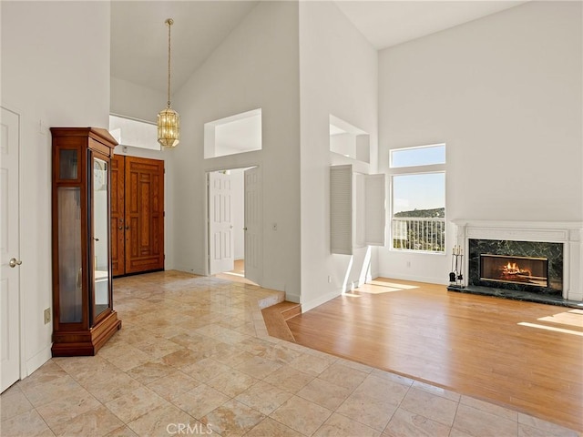 entryway with baseboards, lofted ceiling, a premium fireplace, light wood-style floors, and a notable chandelier